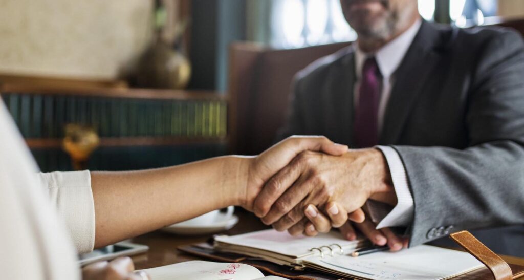 Man shaking hands with a lady over business documents
